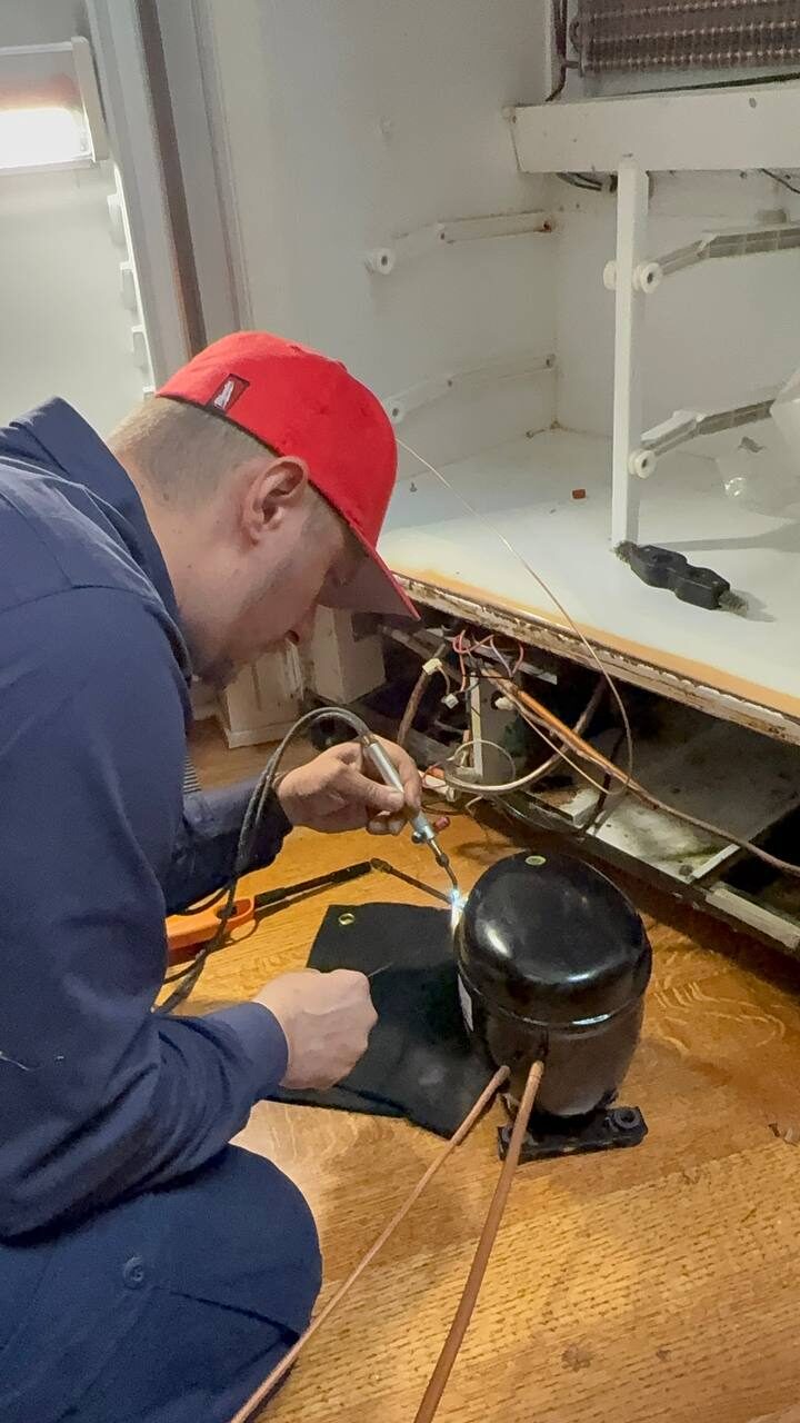 Andrew Kuznetsov brazing a new compressor line during a Sub-Zero 501F sealed-system rebuild