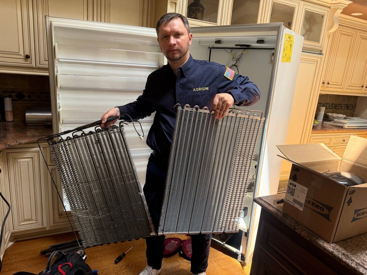 Andrew Kuznetsov, owner and lead technician, holding the old and new evaporator coils from a Sub-Zero 501F sealed-system rebuild